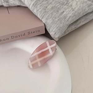 Pink geometric checkered acetate oval hair clip in a cozy lifestyle setting