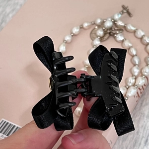 Pince à cheveux élégante avec nœud noir pour coiffure volumineuse sur fond rose