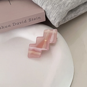 Pink marble geometric hair clip with a stylish stepped design on a white ceramic tray