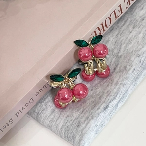 Détail des barrettes cerise avec perles en résine rouge et feuilles en pierre verte