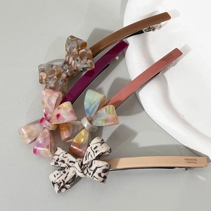 Détail de quatre barrettes à ressort en acétate avec motifs de marbre et textures