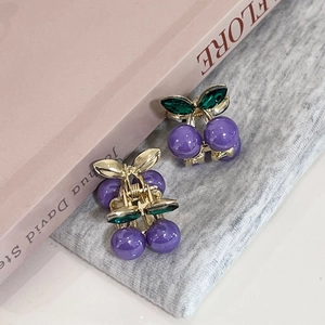 Détail de mini pinces à cheveux cerise avec perles violettes et feuilles en cristal