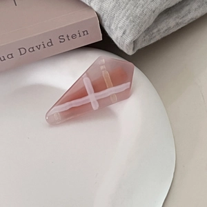Detail of pink geometric checkered hair clip in ceramic tray with aesthetic backdrop