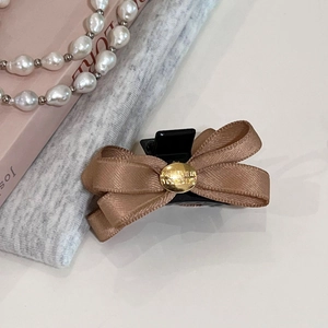 Détail d'une barrette à cheveux nœud marron avec une plaque dorée 'Believe In Yourself'