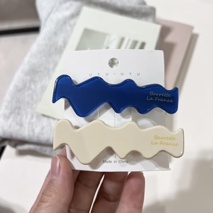Elegant wavy acetate hair clips set in navy blue and cream white on a display card