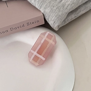Close-up of pink plaid geometric hair clip on a ceramic plate for sweet girl style