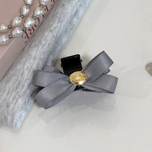 Détail d'une pince à cheveux en satin gris avec breloque dorée gravée de texte motivant