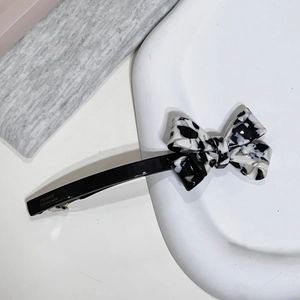 Détail de la pince à cheveux nœud en acétate marbré avec gravure France Handmade sur clip noir