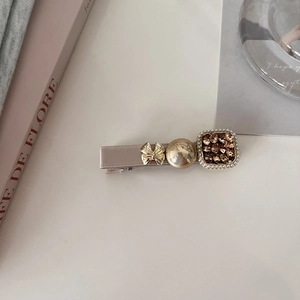 Detail of elegant hair clip with ribbon, gold butterfly, and pearls on a cream surface