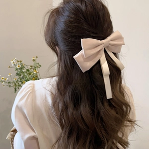 Close-up of elegant pale pink bow hair clip with long ribbons worn on model's hair