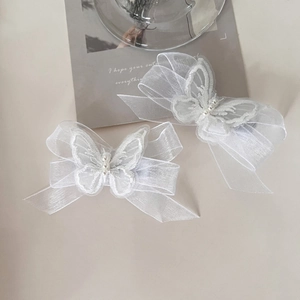 Detail of white mesh butterfly hair clips with delicate embroidery and pearls