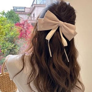 Elegant large pink bow hair clip with flowing ribbons styled on long wavy hair