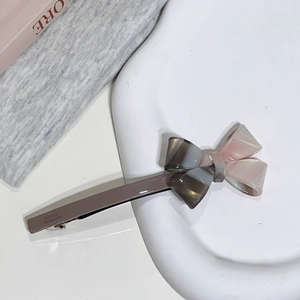 Gros plan détaillé d'une barrette à nœud en acétate tricolore sur un plateau blanc élégant