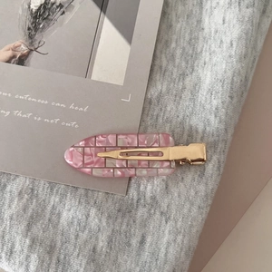 Detail of a pink mosaic acetate hair clip with metal base on aesthetic card background