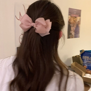Barrette nœud en résille rose élégamment coiffée sur de longs cheveux lisses