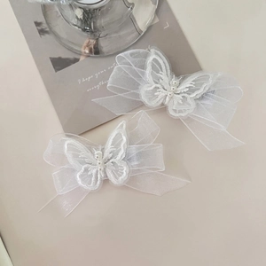 Detail of two white mesh butterfly hair clips with pearl embroidery and elegant tulle fabric