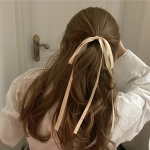 Elegant long beige ribbon bow hair tie shown on a ponytail with soft aesthetic style