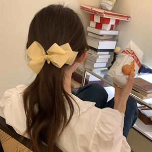 Barrette nœud en tulle jaune pâle avec pendentif doré sur modèle dans un cadre chaleureux