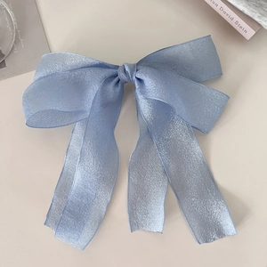 Detail einer hellblauen Schleifen-Haarspange mit schimmernder Textur und eleganten langen Bändern