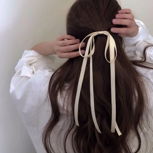 Elegant cream satin long ribbon bow hair tie shown on long wavy brown hair back view