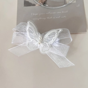 Close-up of white mesh butterfly hair clip with lace embroidery and small pearls