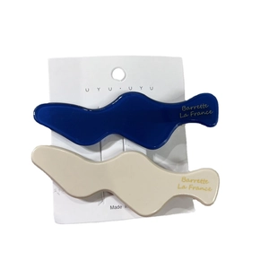 Set of two wavy acetate hair clips in navy blue and cream beige on a card