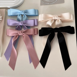 Flat lay of multiple satin bow hair clips with long ribbons in assorted elegant colors