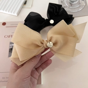 Détail de barrettes à nœuds en résille fine avec breloque dorée et pince à ressort