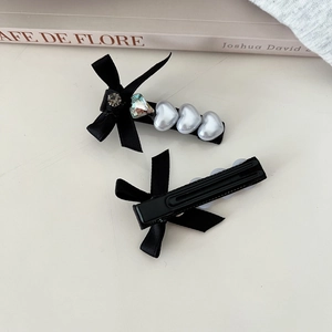 Vue détaillée des barrettes à nœuds en satin noir avec cristaux et perles en cœur