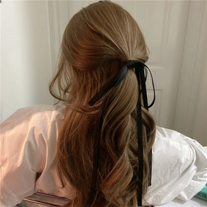 Detail of elegant black long ribbon hair tie styled on wavy brown hair for women