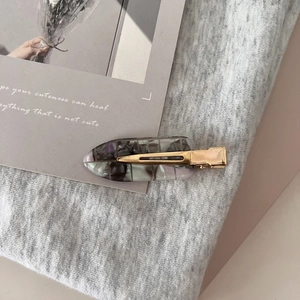 Detailed macro view of acetate marble hair clips on a textured gray background