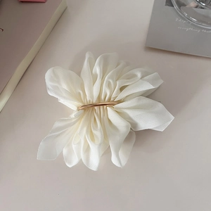 Detailed macro view of an elegant cream white chiffon floral hair clip with gold metal accents