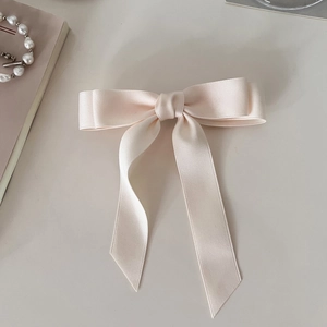 Detail view of pink satin bow hair clip with long ribbons and smooth texture