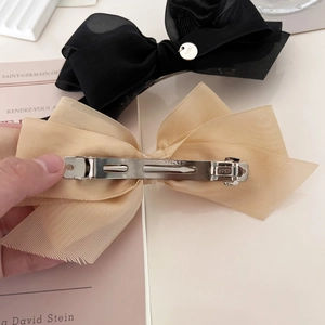 Détail de l'arrière de barrettes à nœuds en résille noir et beige avec pinces à ressort