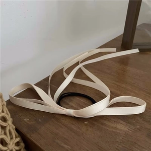 Close-up of a cream satin long ribbon hair tie with smooth texture on a wooden surface