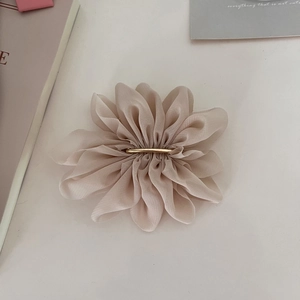 Detail view of champagne chiffon flower hair clip with delicate pleated fabric petals