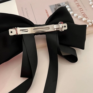 Close-up of elegant black satin bow hair clip with a silver metal barrette spring