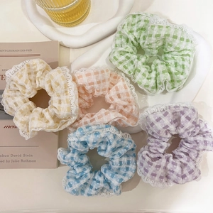 Detail view of colorful plaid scrunchies with white lace edges in various pastel tones