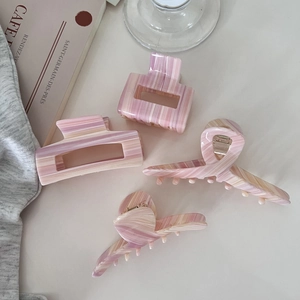 Set aus rosa Marmor-Haarklammern mit vier Acetat-Haarspangen auf beigem Hintergrund