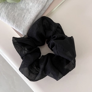 Detail shot of the black sheer organza fabric texture on a ruffled large hair scrunchie