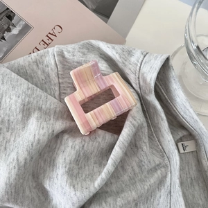 Detail der rosa und lila gestreiften Marmor-Haarklammer auf grauem Textilhintergrund