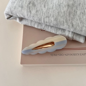 Gros plan sur une pince à cheveux ondulée en acétate dégradé avec base en métal doré