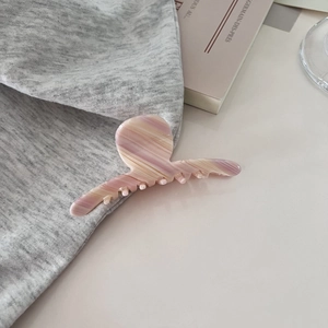 Detaillierte Makroansicht der rosa marmorierten Haarklammer auf grauem Textil