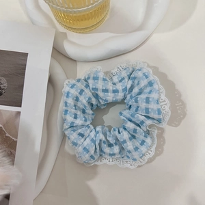 Close-up of blue plaid scrunchie with lace trim on a decorative tray background
