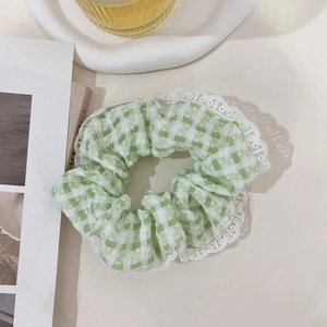 Close-up of light green plaid scrunchie with white lace trim on a white tray