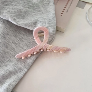 Detail einer Haarspange mit rosa Marmorverlauf auf grauem Strickgewebe