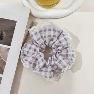 Close-up of lilac checkered scrunchie with lace edge on a creamy white aesthetic background