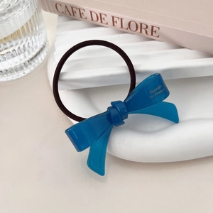 Macro view of a blue acetate bow hair tie with gold lettering and high elastic band