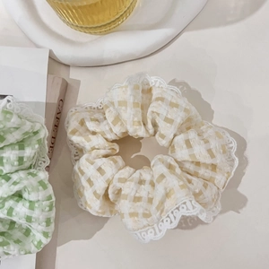 Close-up of cream and green plaid scrunchies with elegant white lace trim details