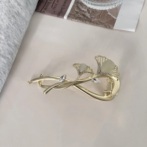 Détail de la pince à cheveux ginkgo dorée avec pierres œil de chat et petits diamants